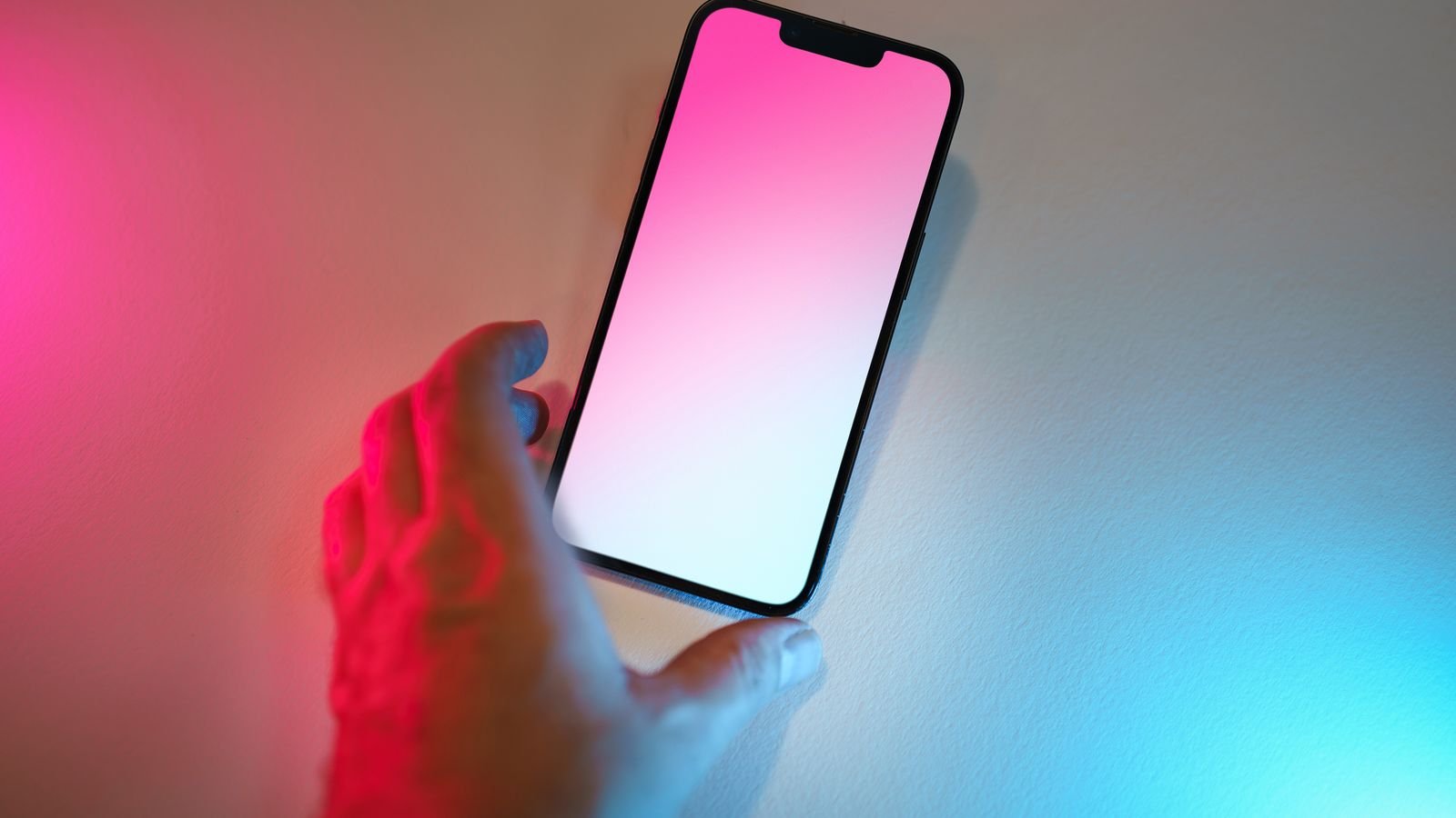 A hand reaching for a smartphone displaying a colorful gradient screen, representing Google's new Pixel 11 launch