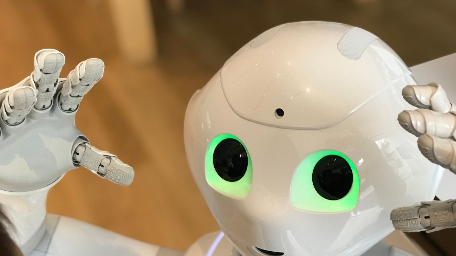 A white humanoid robot with glowing green eyes, representing autonomous vehicle technology and AI-driven robotics