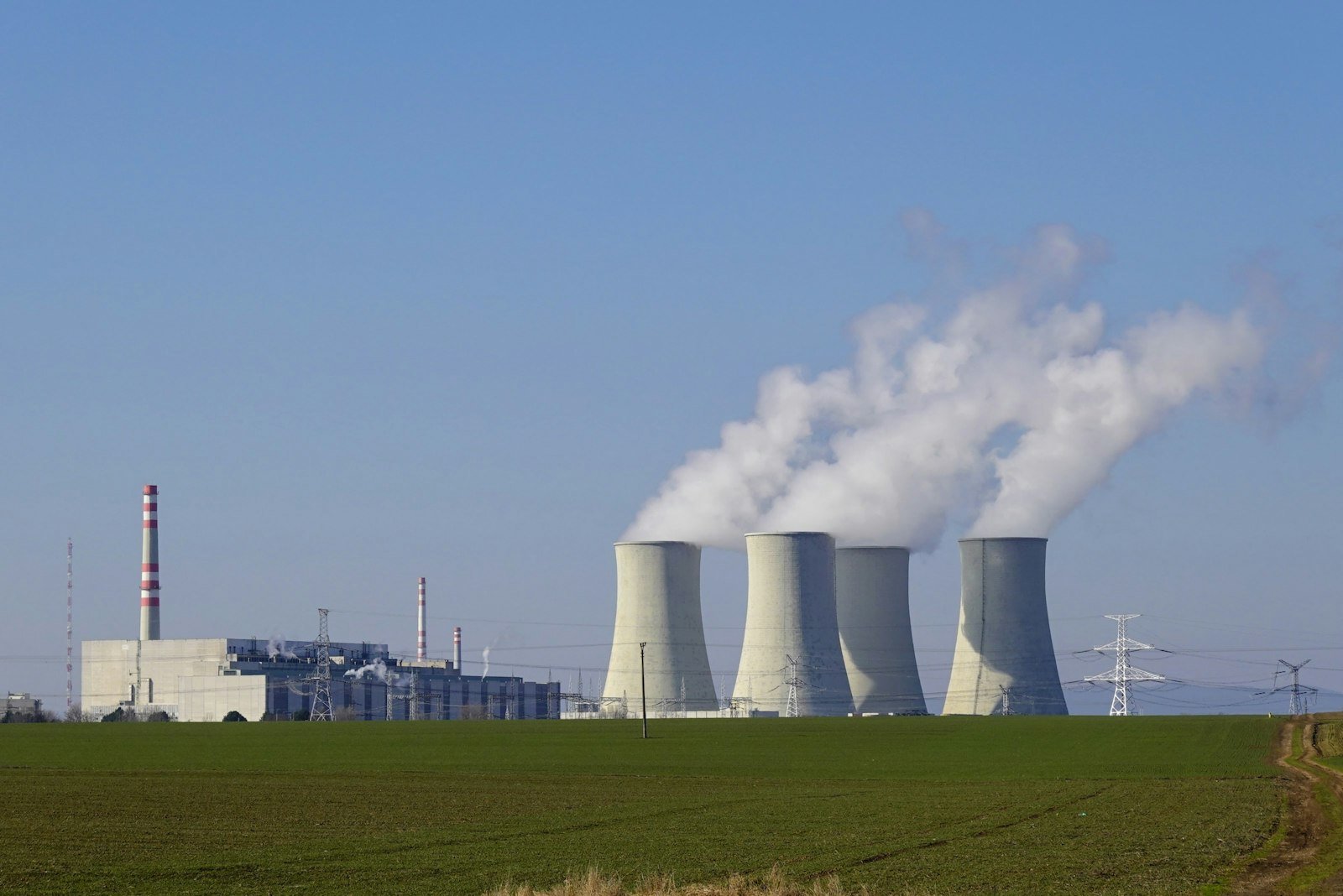 Nuclear power plant cooling towers releasing steam under a clear blue sky