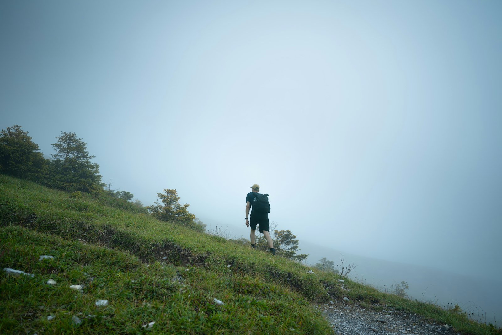 Hiker with backpack on a foggy mountain trail, beyond cell coverage